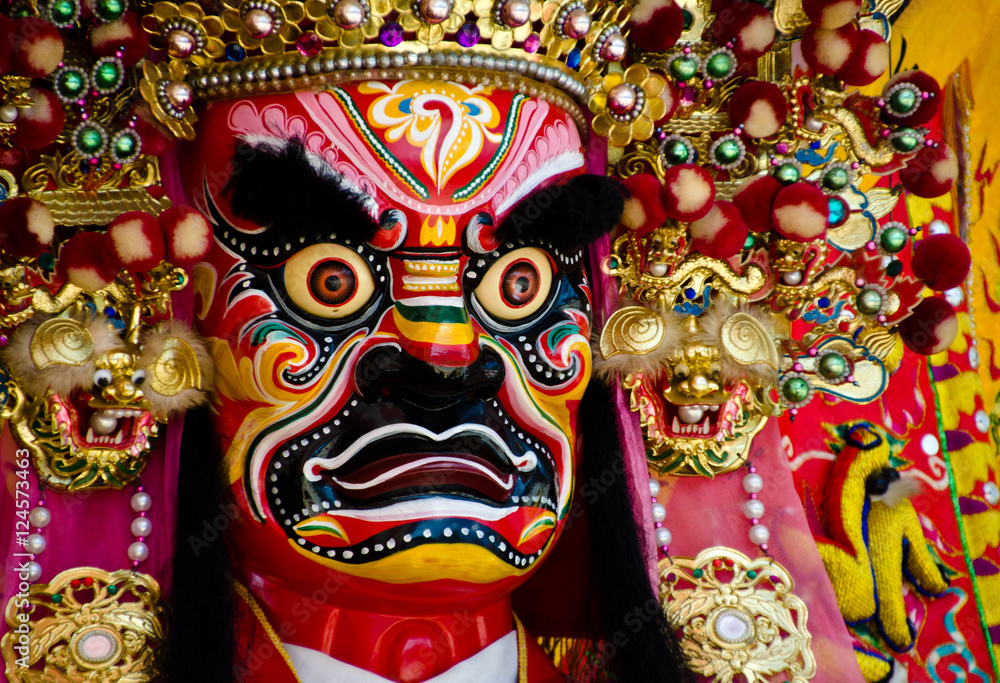 Fototapeta premium Colorful face of a Chinese deity. The face of the diety and the head ornament are refined pieces of artwork. There are red, pink, yellow, white, yellow, blue and green colors on it.