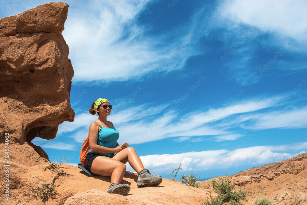 The beautiful girl on a background of orange rocks and blue sky.