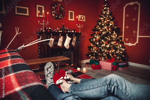 A couple of lovers resting by the fireplace in the Christmas room. Feet in woolen socks warming in winter time.