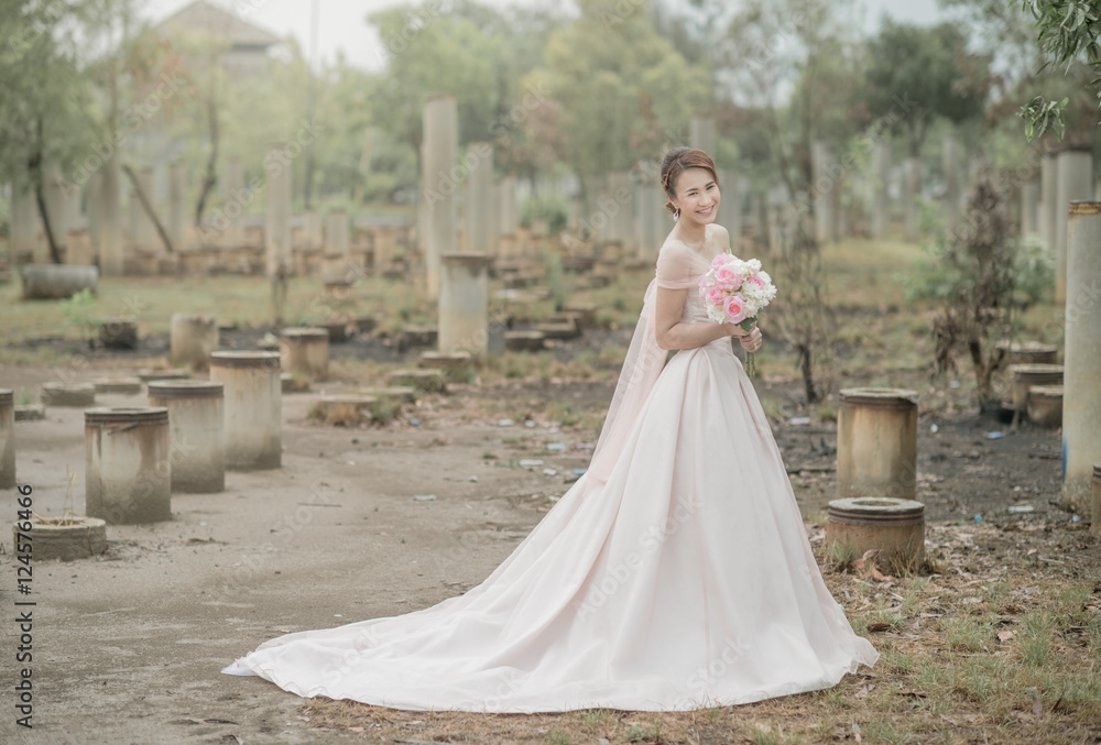 Beauty bride in bridal gown with bouquet outdoors. Beautiful model girl in a pink wedding dress. Female portrait of cute lady. Woman with hairstyle Beauty bride in bridal gown with bouquet outdoors. Beautiful model girl in a pink wedding dress. Female portrait of cute lady. Woman with hairstyle