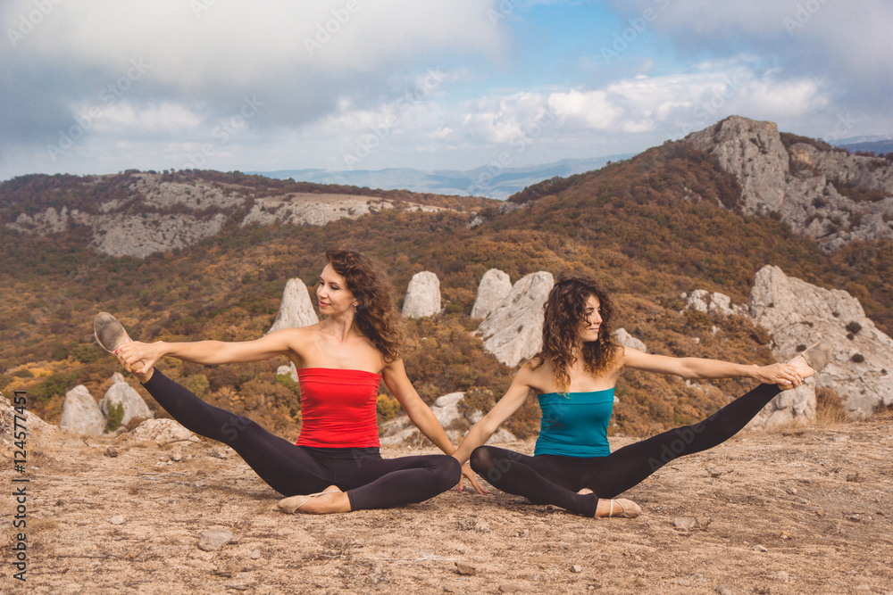 Two girls are doing yoga in mountains landscape Two girls are doing yoga in mountains landscape
