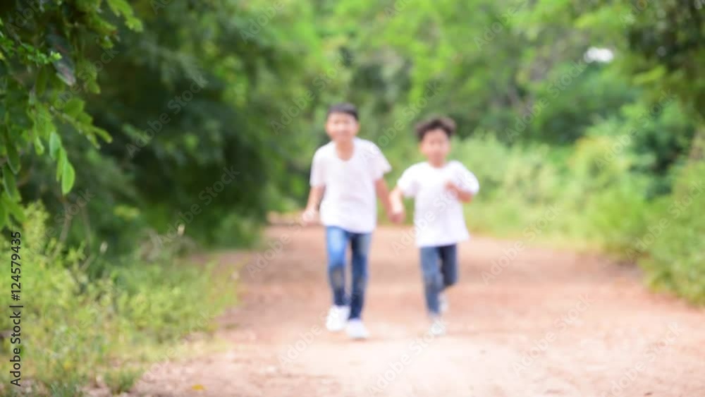 Slow motion Two young Thai boy run together on the crack road in the natural park. Slow motion Two young Thai boy run together on the crack road in the natural park.