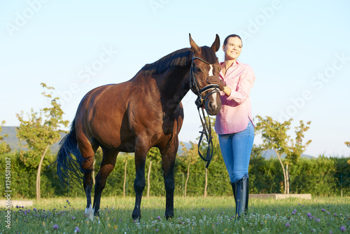 Beautiful young woman with her bay horse