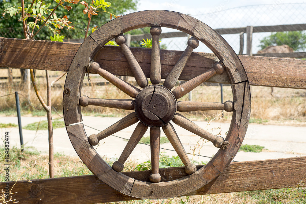 Old wooden wheel decorates the fence.