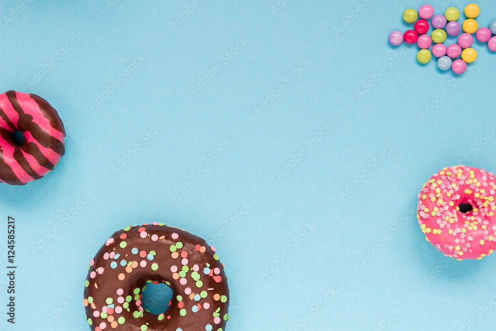 Sweet donuts with colorful candies on the blue background. Sweet donuts with colorful candies on the blue background.