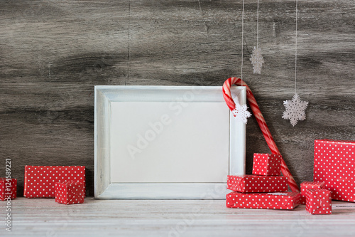 White photo frame with christmas decoration on the wooden table. Greeting card template