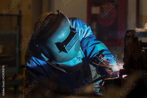 Worker is welding steel part in  factory