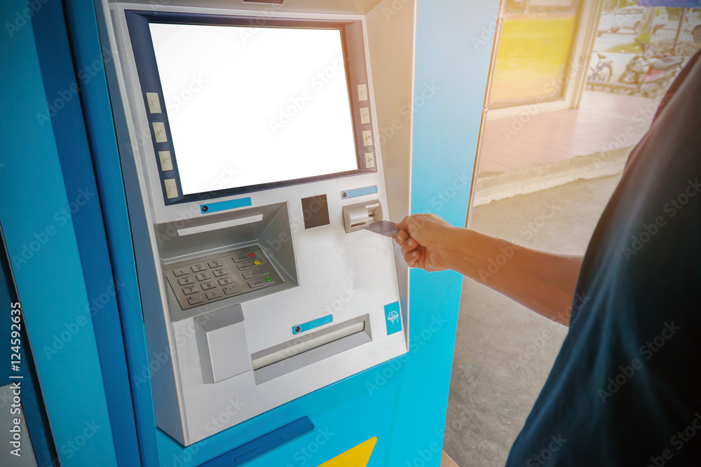 A man uses an ATM card inserted into the ATM machine for cash. A man uses an ATM card inserted into the ATM machine for cash.