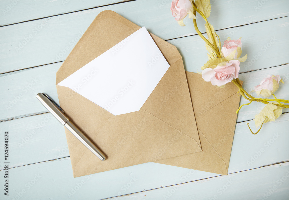 An open brown envelope with letter and writing pen on a blue wooden background An open brown envelope with letter and writing pen on a blue wooden background
