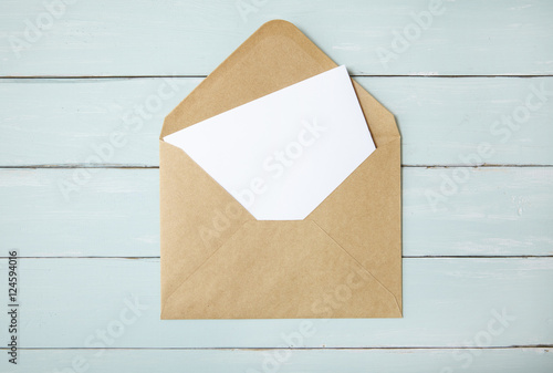 An open brown envelope with letter on a blue wooden desk top background