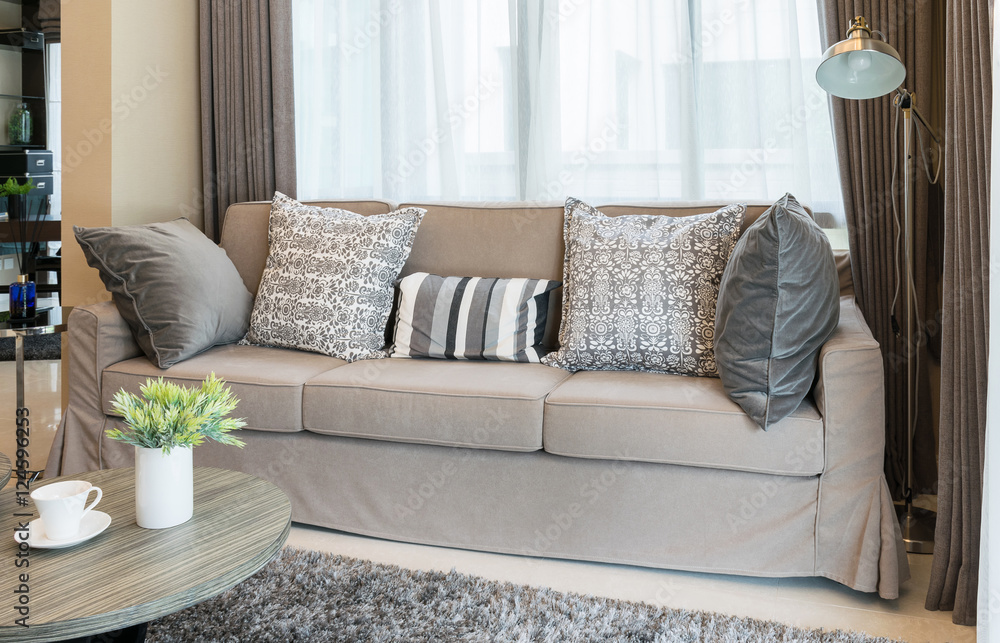 Fototapeta premium Sturdy brown tweed sofa with grey patterned pillows
