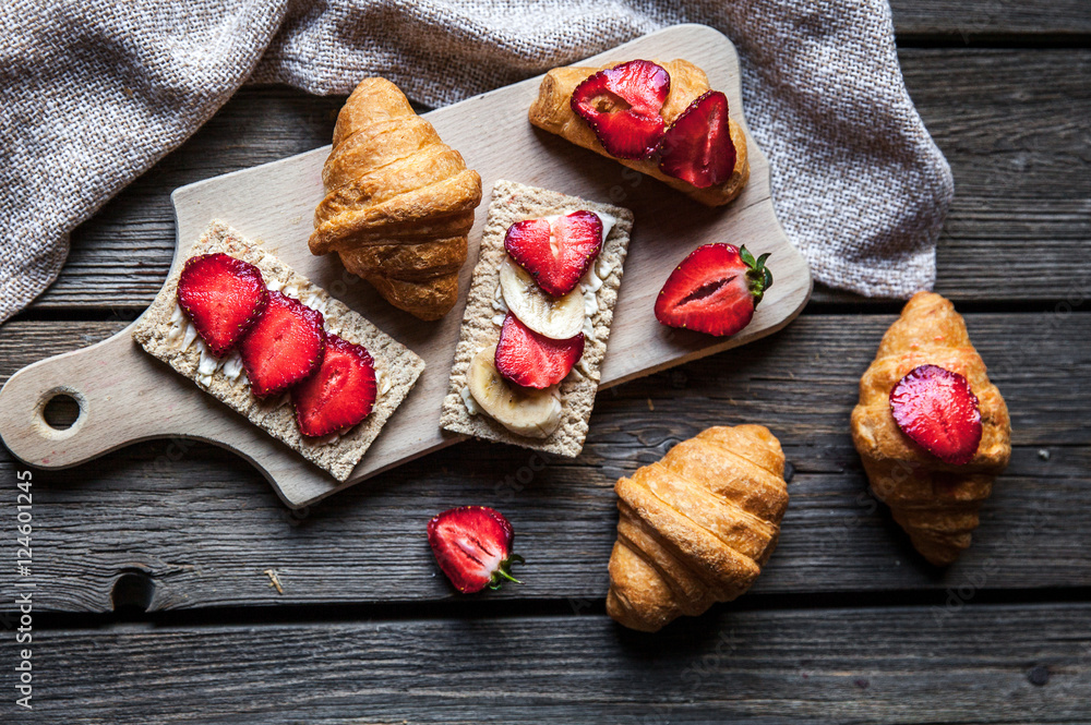 A delicious breakfast of strawberries and bread on wooden background. Fruit, food, sandwiches, cheese. Vintage style.