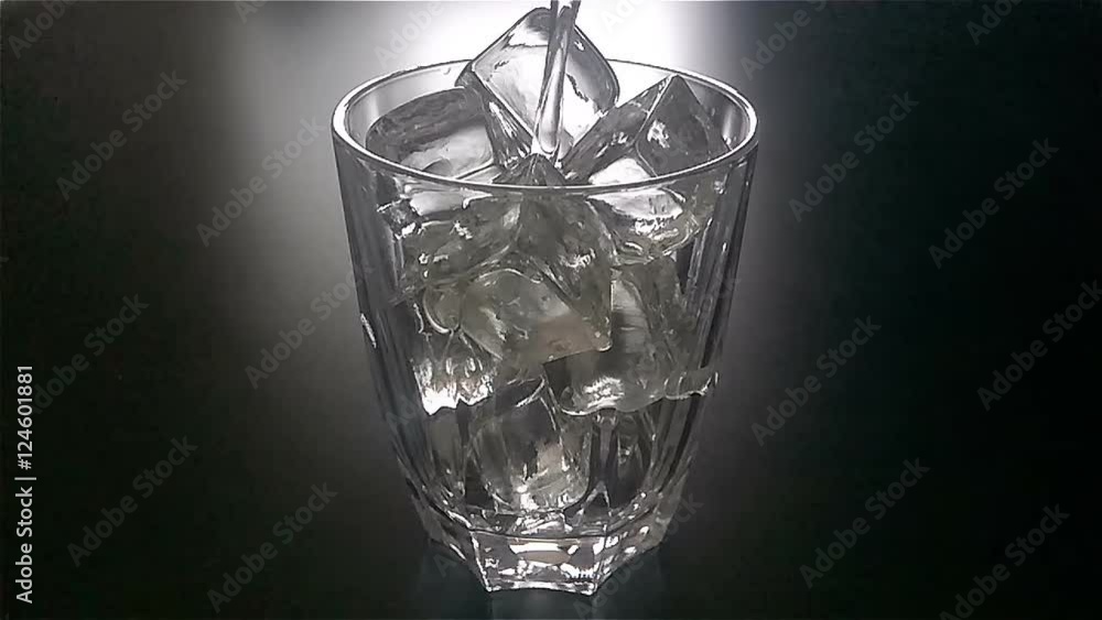 pouring glass of water with ice cubes in slow motion at 120fps in dark pouring glass of water with ice cubes in slow motion at 120fps in dark