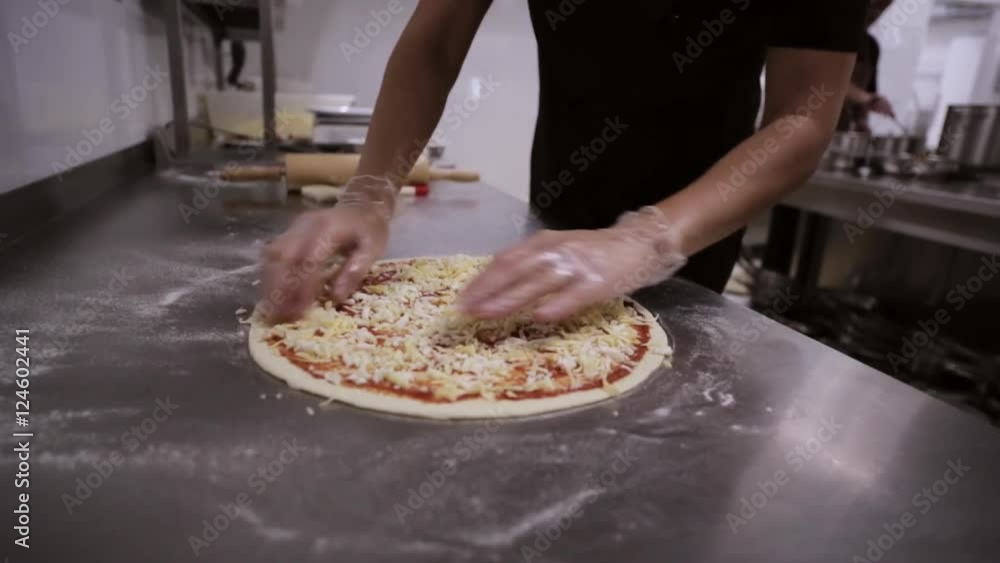 Chef putting cheese topping on his pizza base. Chef putting cheese topping on his pizza base.