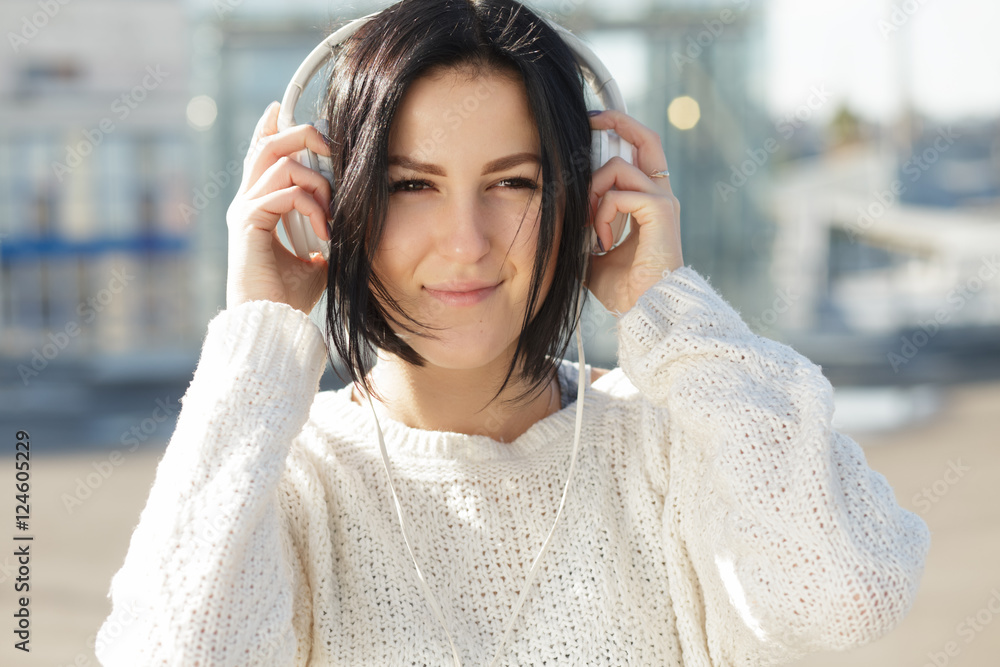Woman in white earphones enjoying to listen music in city