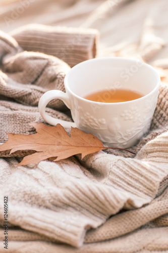 Warm knitted sweater,cup of hot tea and red thermos