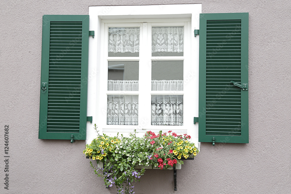 Window with green shutters, on the windowsill, a potted with flowers Window with green shutters, on the windowsill, a potted with flowers