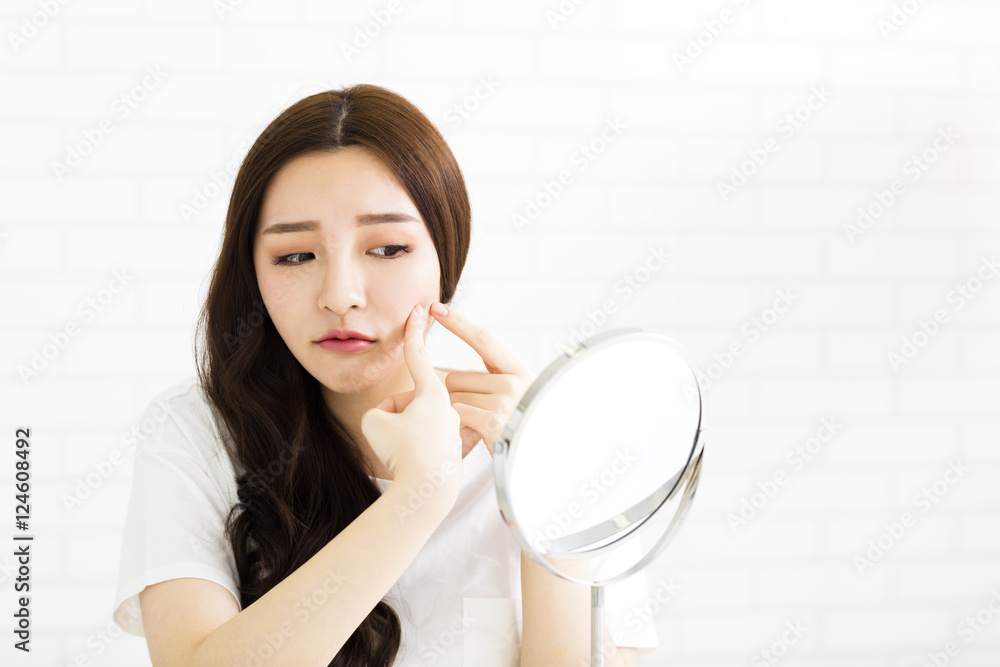 young woman squeeze her acne in front of the mirror young woman squeeze her acne in front of the mirror