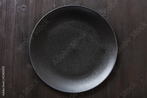top view of black plate on dark brown table