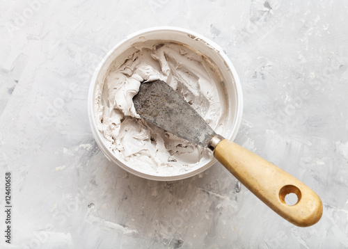 фотографія metal spatula with wooden handle in pot with putty