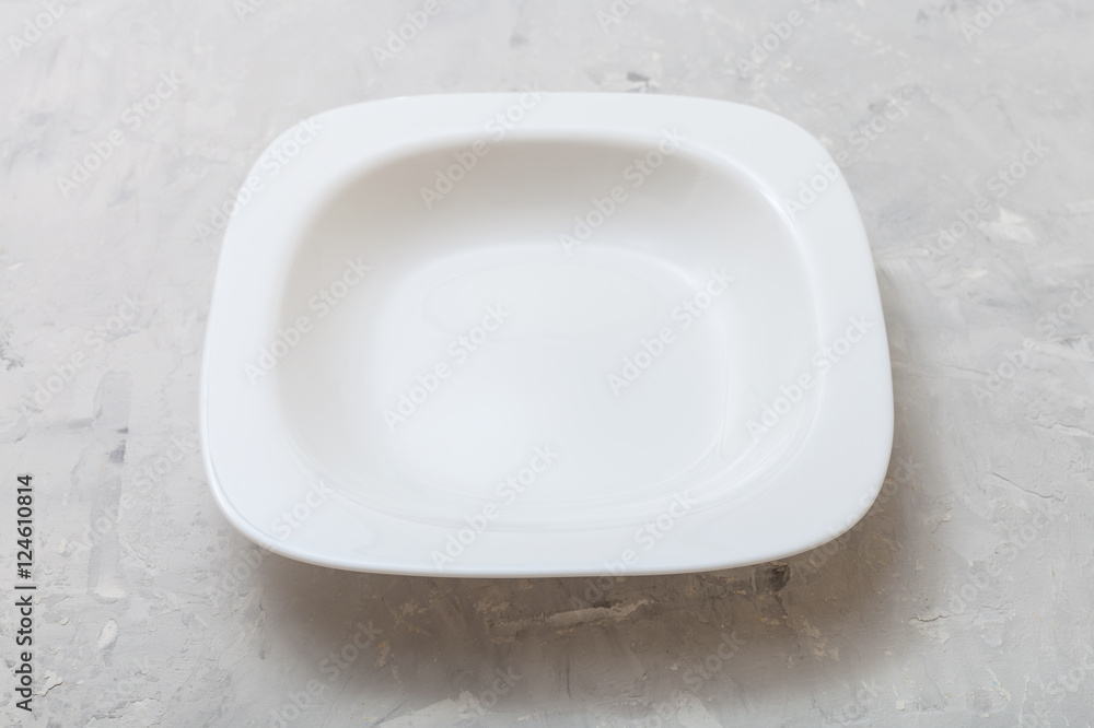 one square white deep plate on gray concrete one square white deep plate on gray concrete