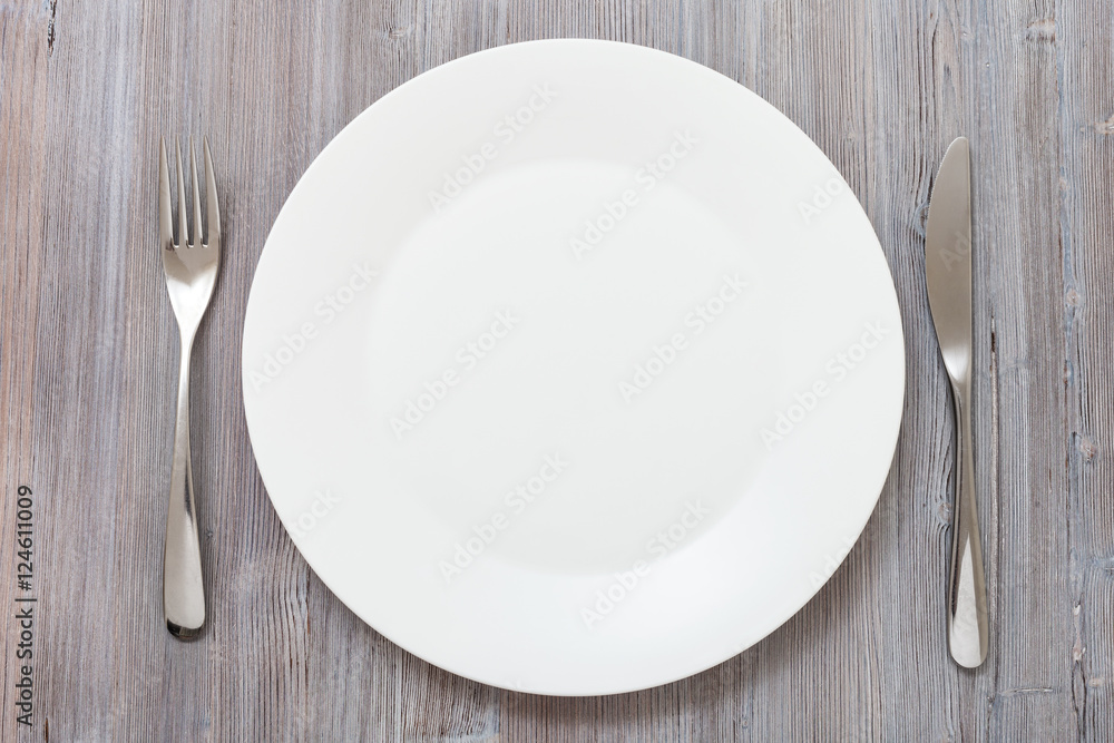 top view of white plate, knife, spoon on gray top view of white plate, knife, spoon on gray