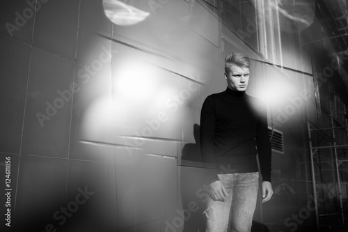 Black and white artistic photography. Young blonde man standing on street