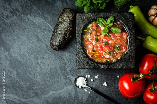 Tomato sauce salsa and ingredients dark stone background. Top view
