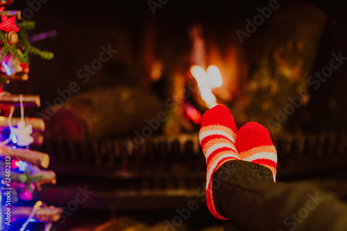 Woman feet in wool socks warming by fireplace