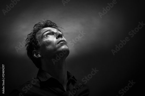 Isolated thinker man face looking up. Low key , black and white portrait. Hope concept