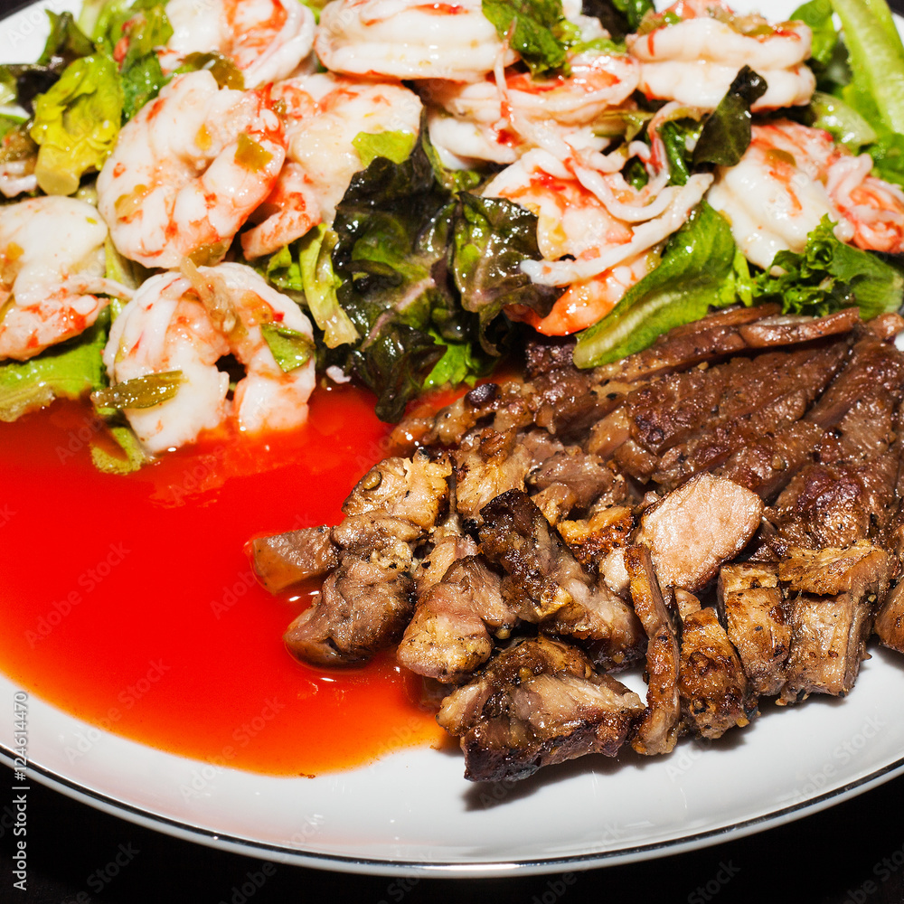 Pork steak with shrimp salad on white plate Pork steak with shrimp salad on white plate