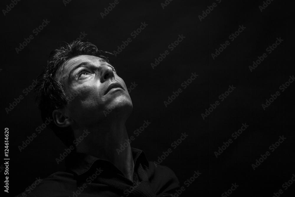 Fototapeta premium Isolated thinking man face looking up. Low key , black and white portrait.