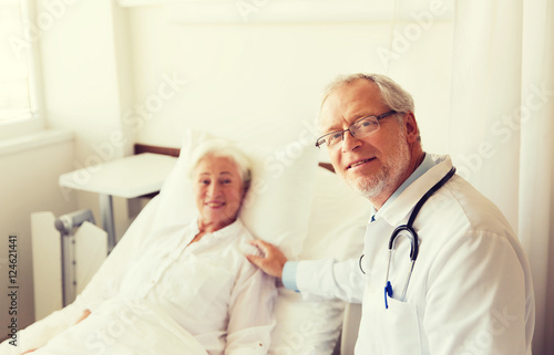 doctor visiting senior woman at hospital ward