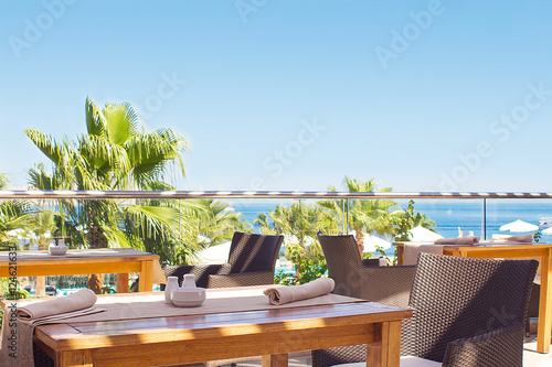 outdoor terrace of restaurant overlooking the sea and palm trees