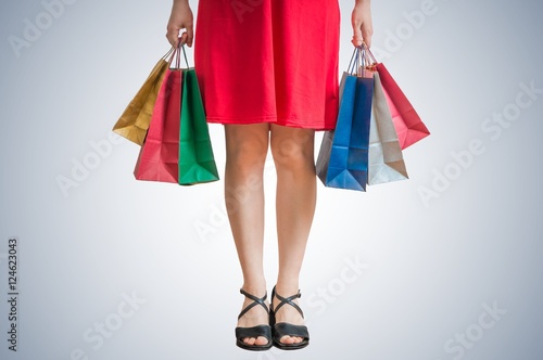 Legs of shopping woman holding many colorful bags in hands.