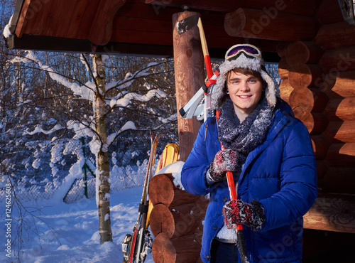 Young man with ice hockey skates and stick at winter cottage