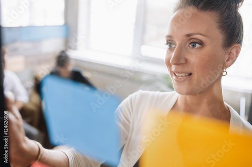 Young woman looking over a post it note