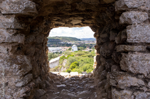 Old windmill through small window in fortress wall, Obidos