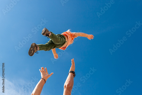 The elder brother throws his younger  on the beach against the backdrop of the sea. Happy carefree childhood