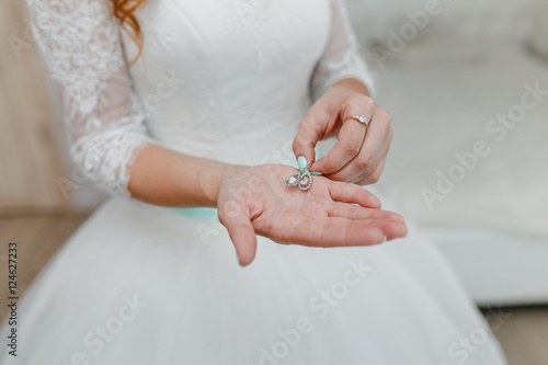 Wedding earrings on a bride's hand, bridal morning fees © EdNurg