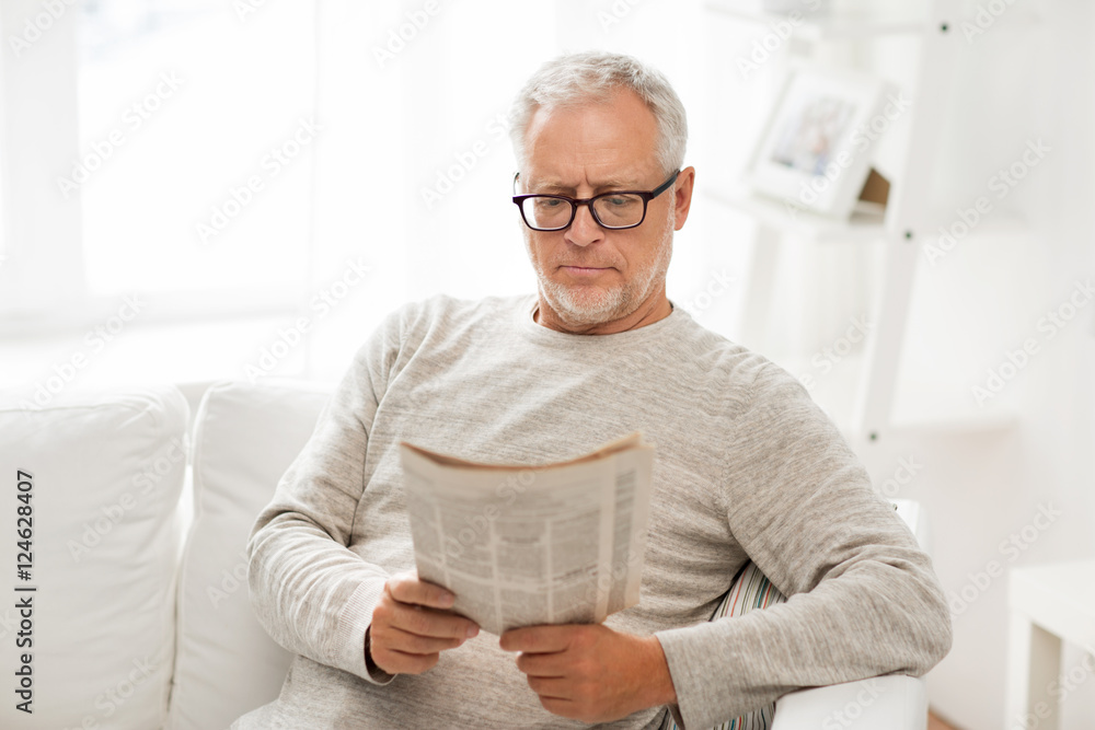 senior man in glasses reading newspaper at home senior man in glasses reading newspaper at home