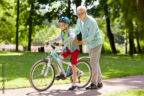 grandfather and boy with bicycle at summer park