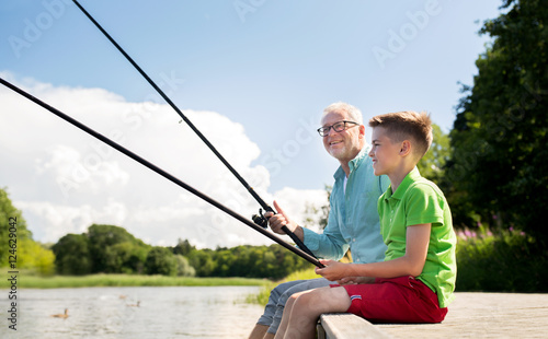 grandfather and grandson fishing on river berth