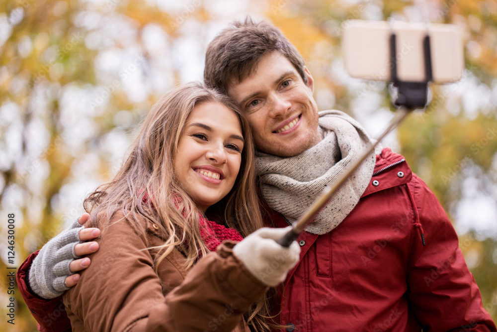 couple taking selfie by smartphone in autumn park couple taking selfie by smartphone in autumn park