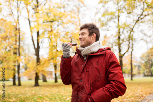 man recording voice on smartphone at autumn park