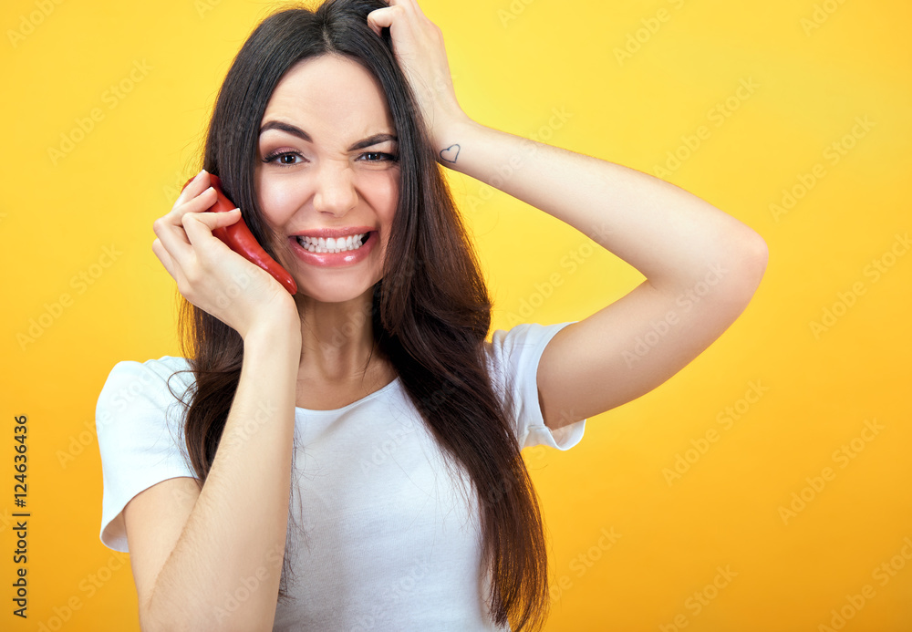 Hipster girl holding red hot chilli pepper near her face like sm Hipster girl holding red hot chilli pepper near her face like sm