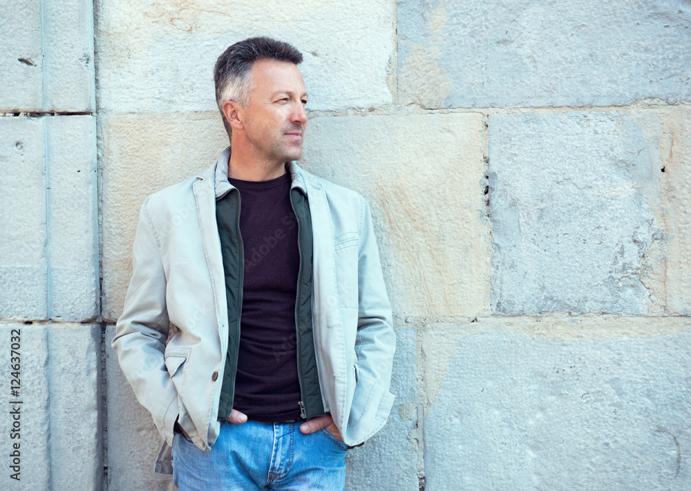 Obraz premium Handsome middle-aged man posing over old ancient street wall, Pa