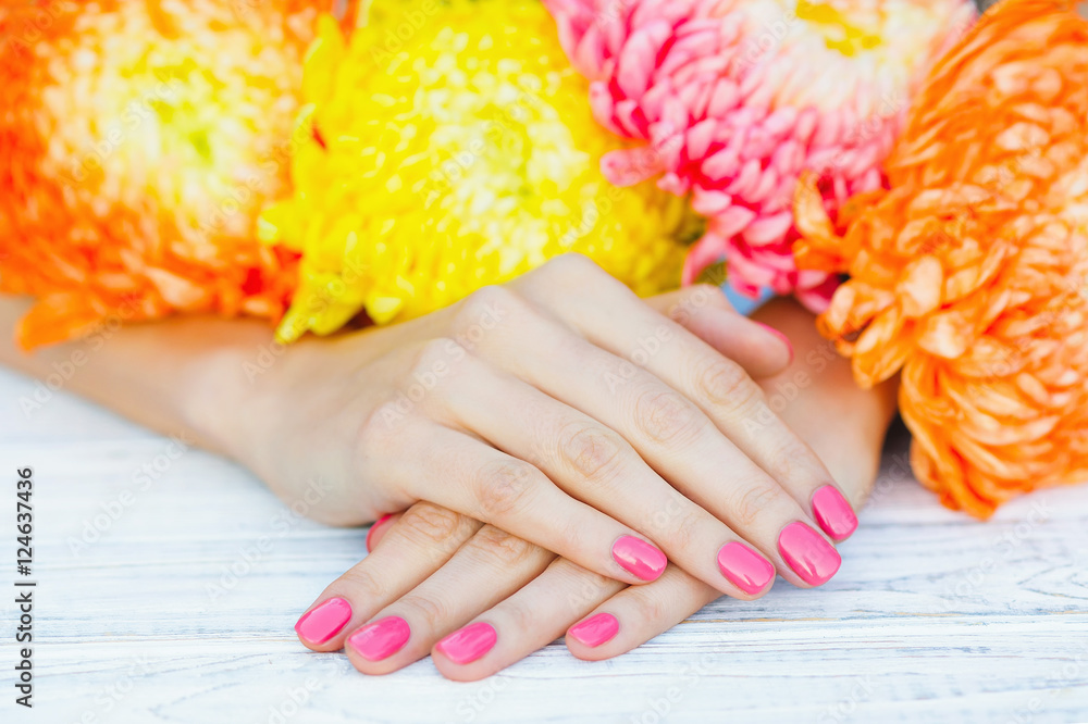 Fototapeta premium Woman hands with manicured fingernails surrounded by bright autumn flowers