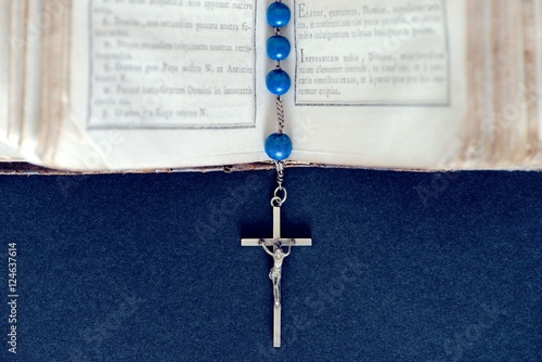 Blue Christian cross necklace on open Holy Bible