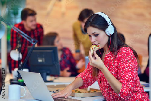 Canvas Print Cheerful office girl enjoying pizza at lunchtime